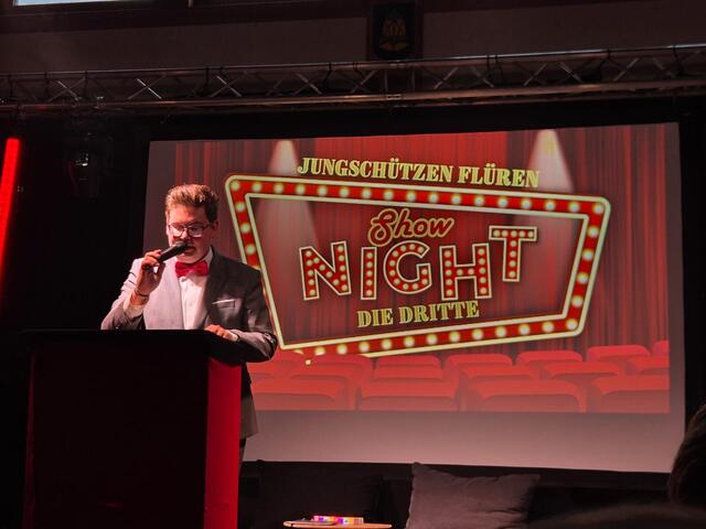 Moderation vor dem Logo der Show Night – Die Dritte
